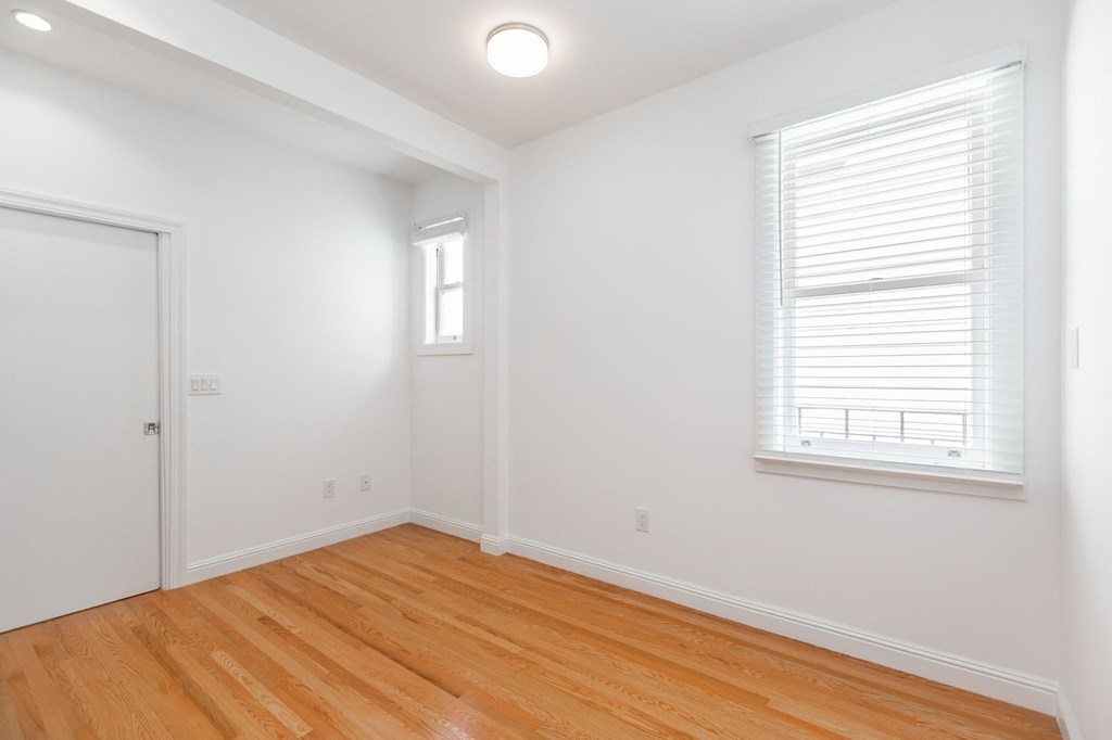 A room with a white door and a window with blinds.