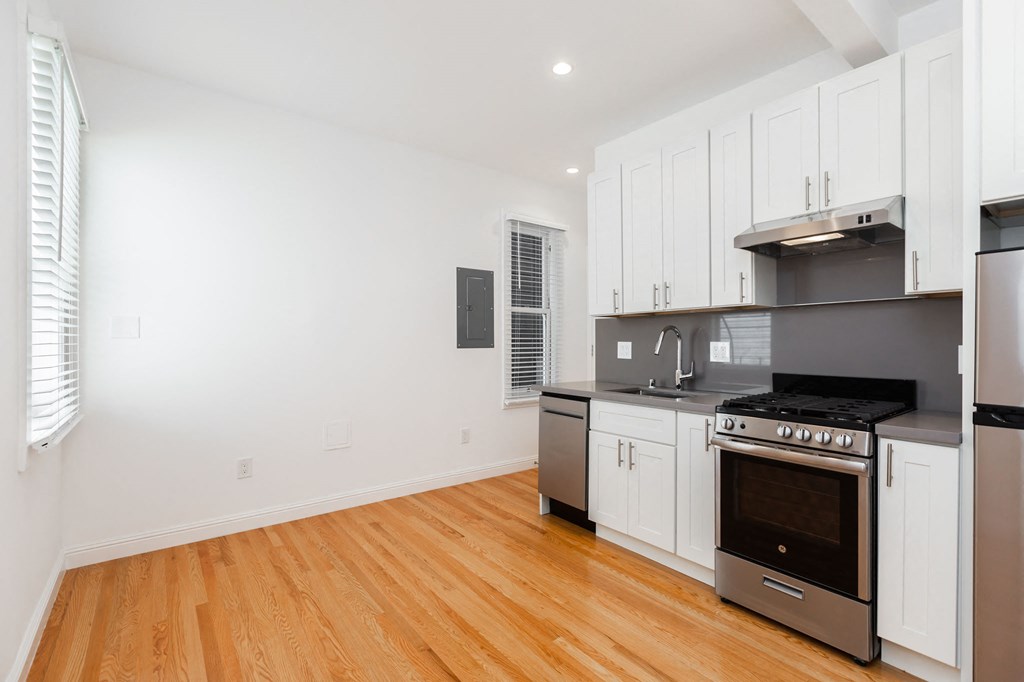 A kitchen with white cabinets and a wooden floor.