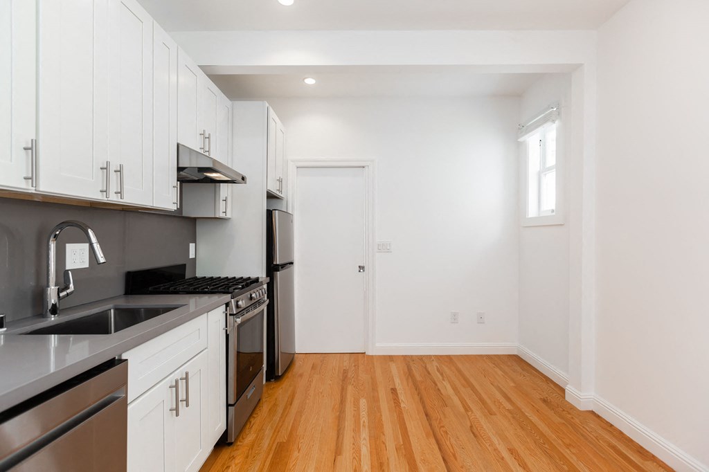 A kitchen with white cabinets and black appliances.