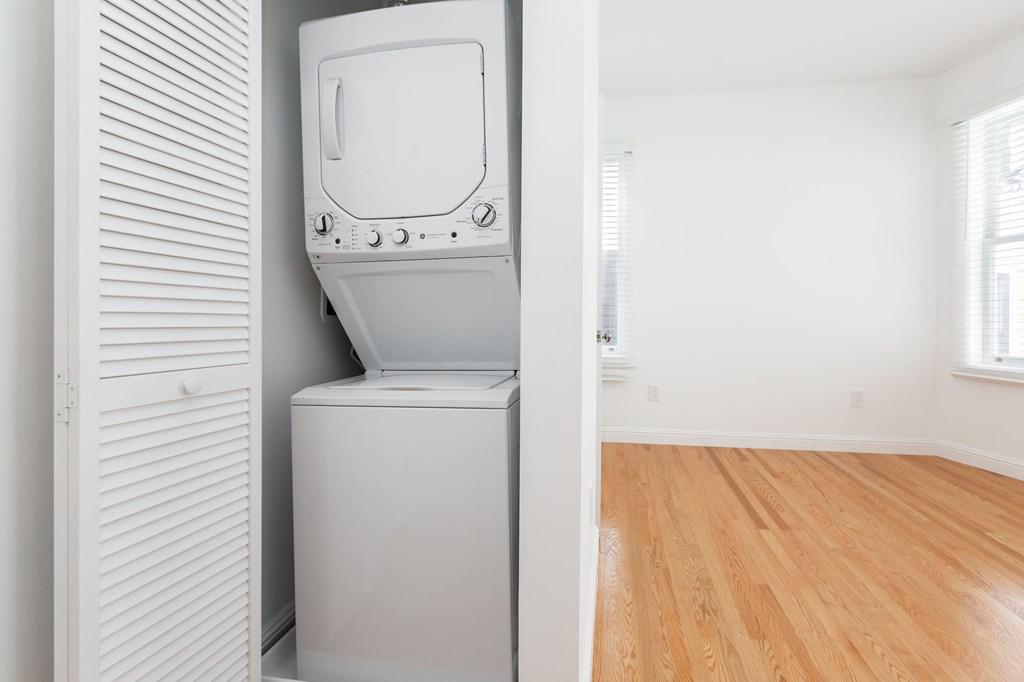 A white washing machine in a room with wooden floors.