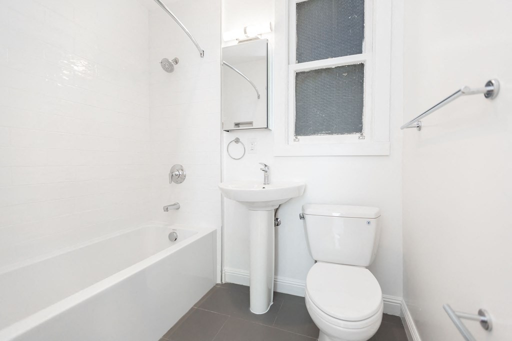 A white bathroom with a toilet, sink, and bathtub.