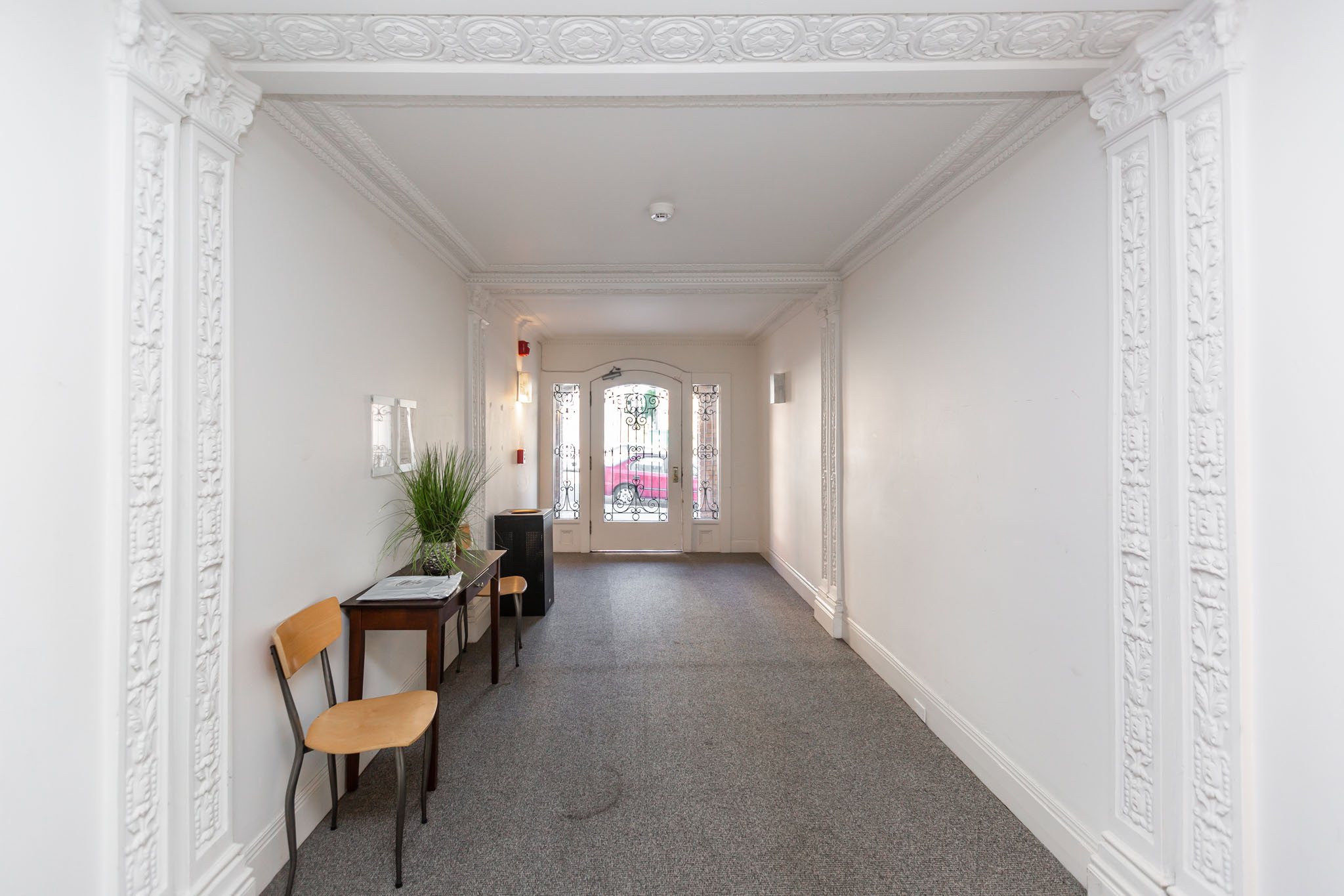 A long white hallway with a table and chairs on the left side.