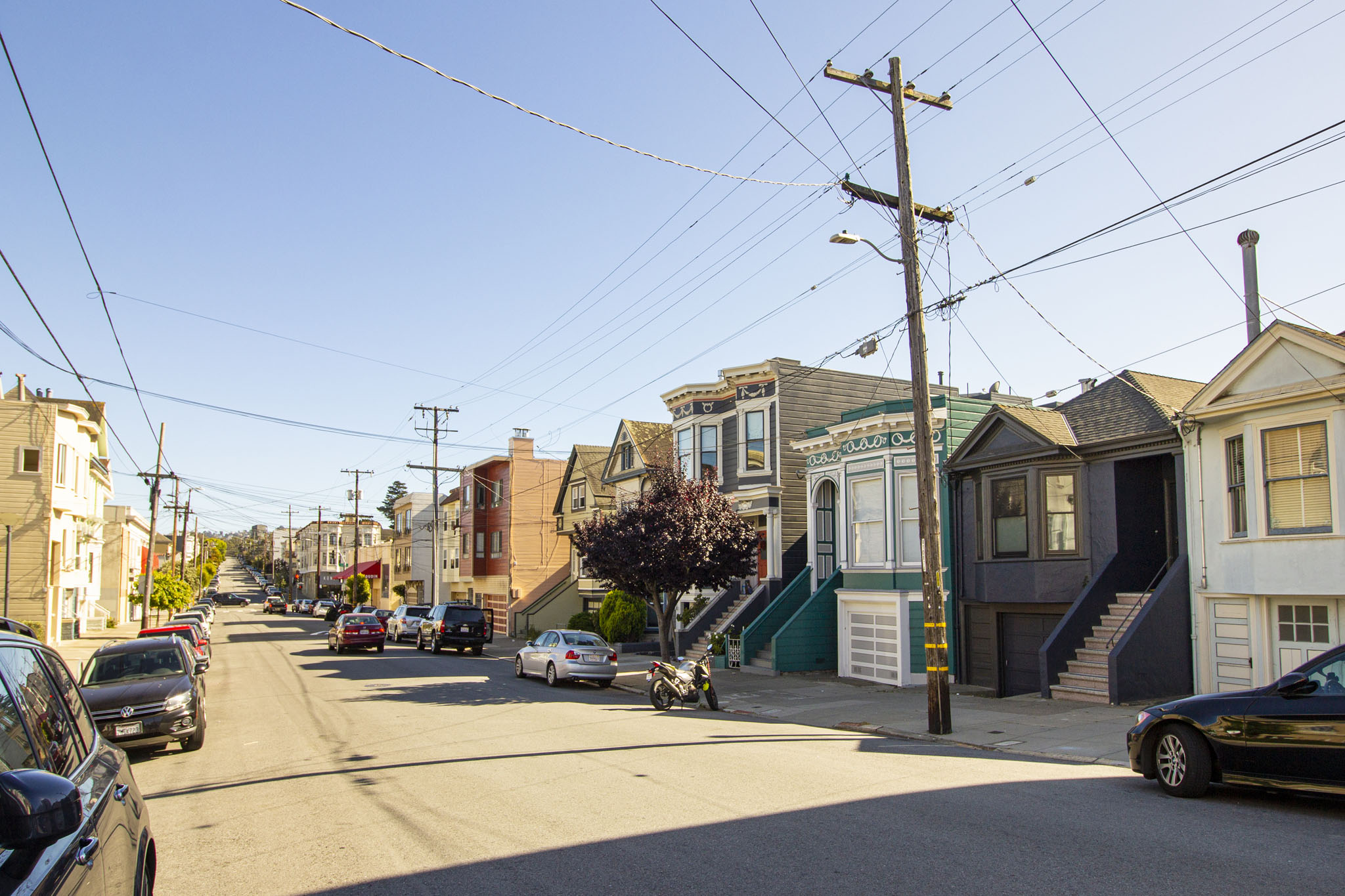 A street view of a residential area with cars parked on the side of the road.