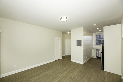 A large empty room with a kitchen in the background.