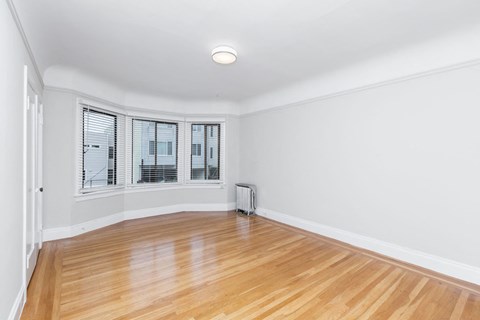 A room with wooden floors and a window with blinds.