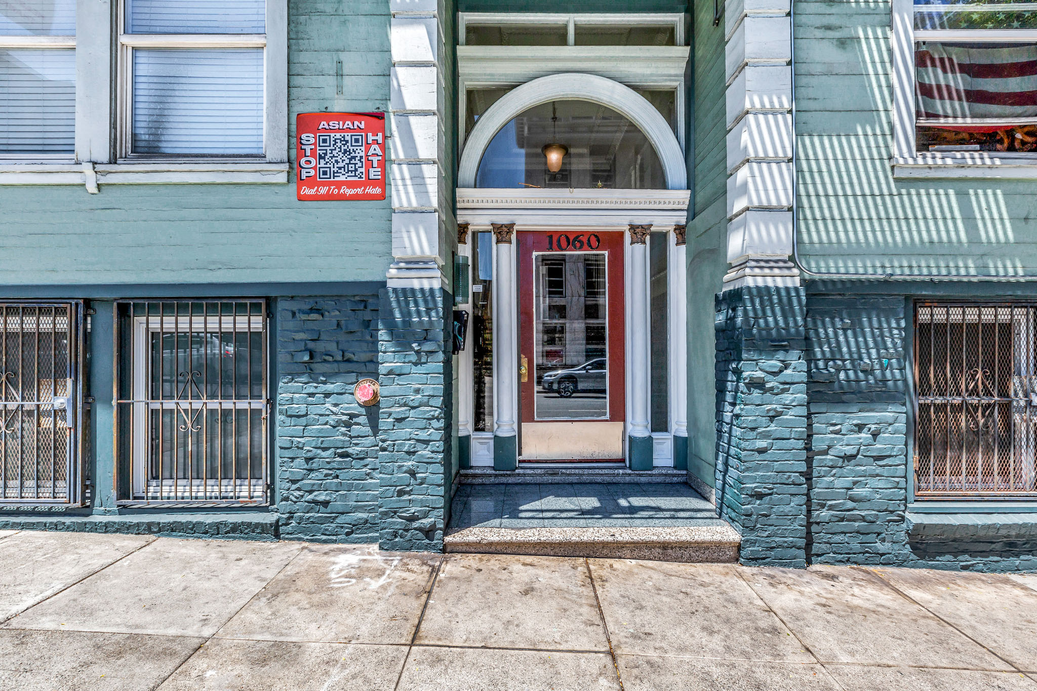 A blue building with a red door and a sign on the left.