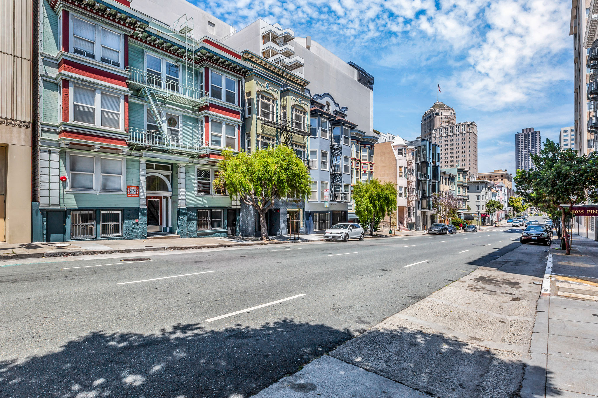A street view of a city with buildings on the side and cars on the road.