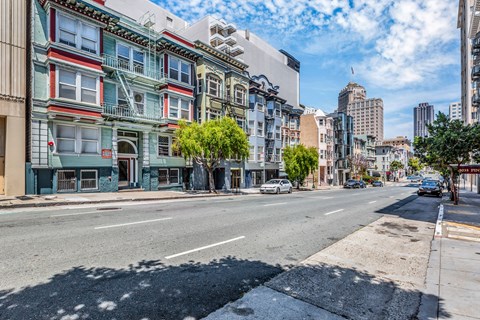 A street view of a city with buildings on the side and cars on the road.