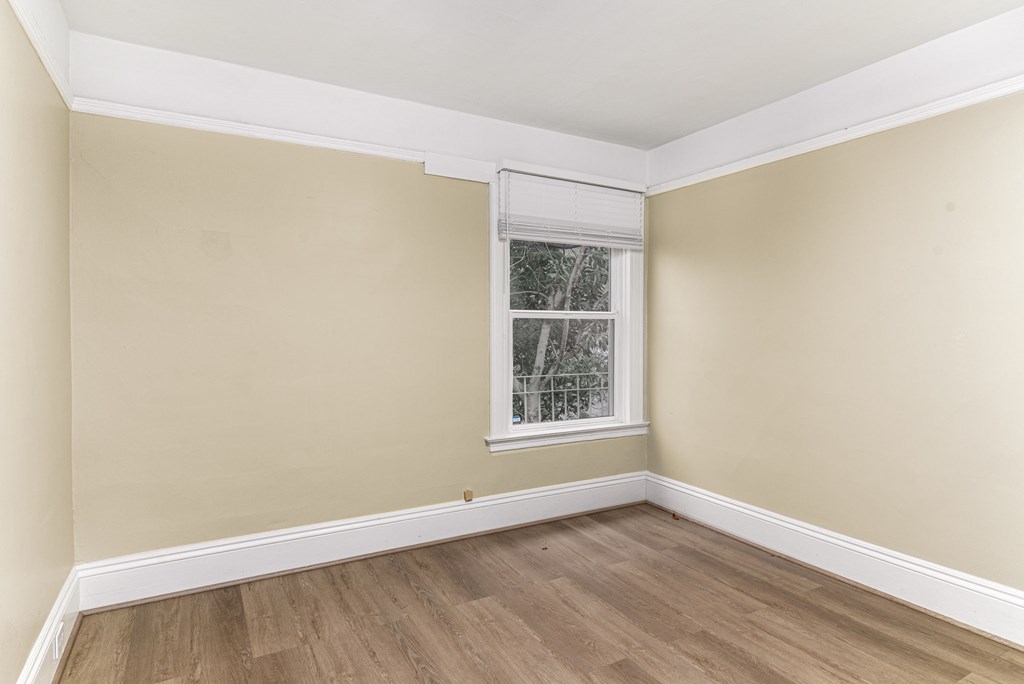 A room with a window and wooden flooring.