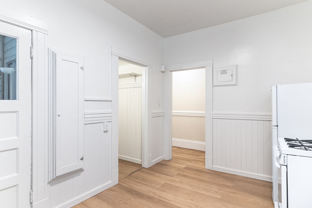A white kitchen with wood floors and a white fridge.