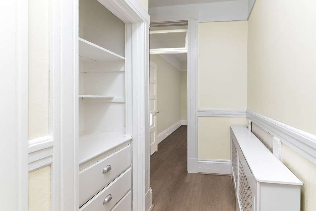 A white closet with a bench and drawers.