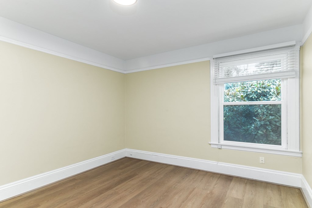A room with a window and wooden flooring.
