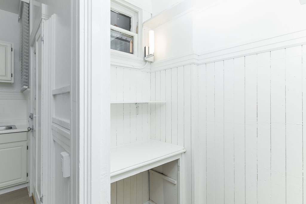 A white kitchen with a refrigerator and a shelf.