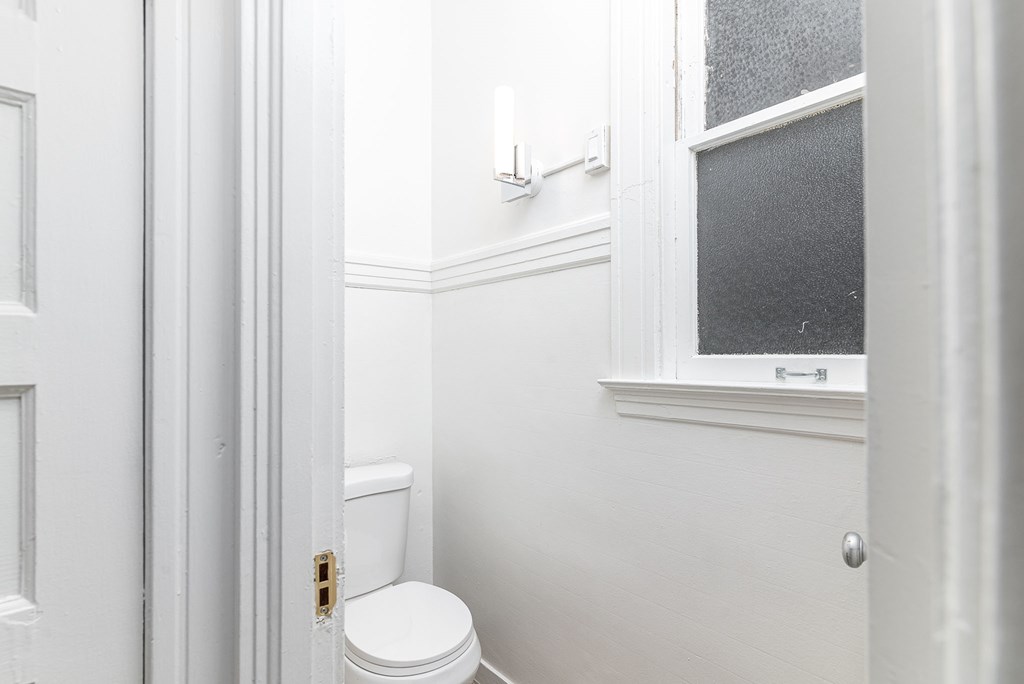 A white toilet in a small bathroom with a window.
