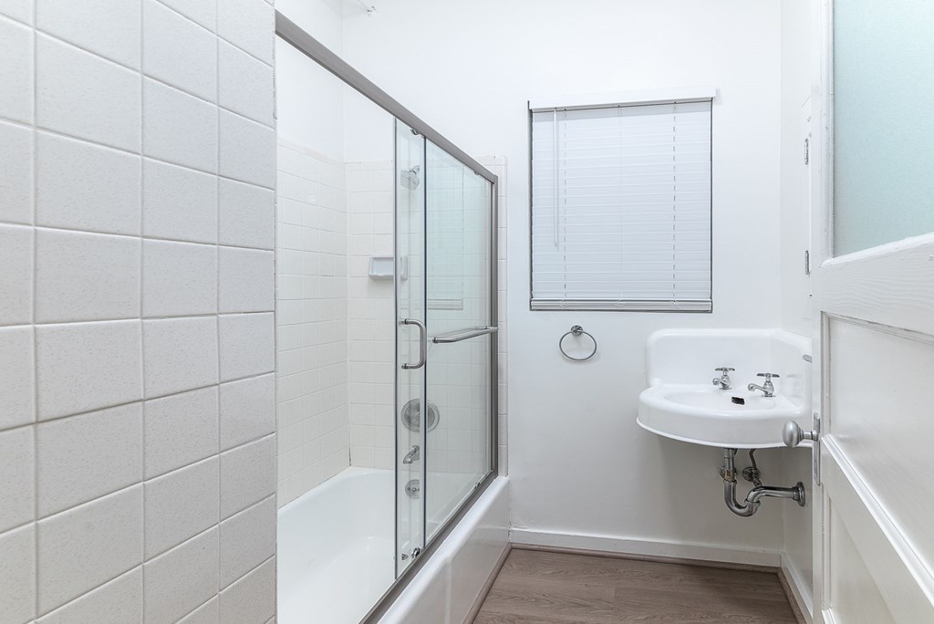 A white bathroom with a sink, mirror, and shower.