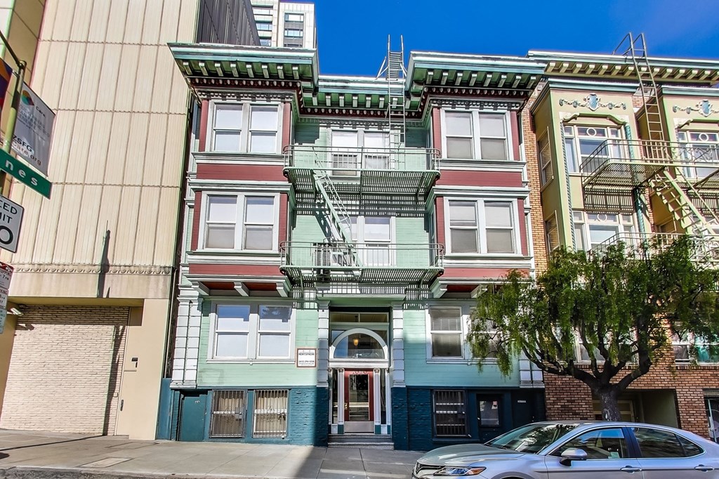 A row of colorful buildings with a tree in front of the first one.