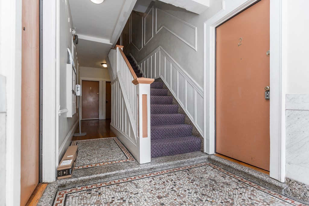 A hallway with a staircase and a door.