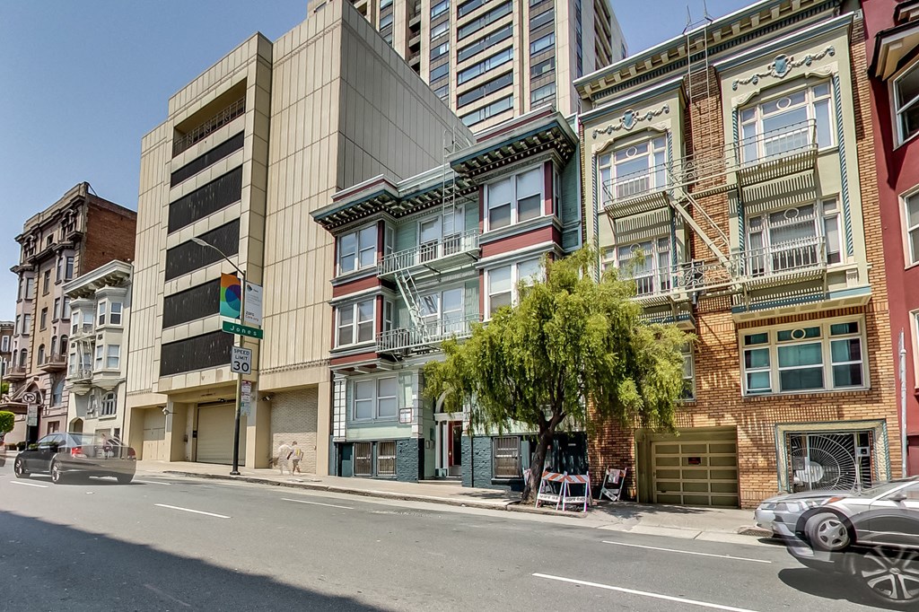 A street view of a city with buildings, cars, and a tree.