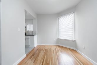 an empty living room with wood floors and a kitchen