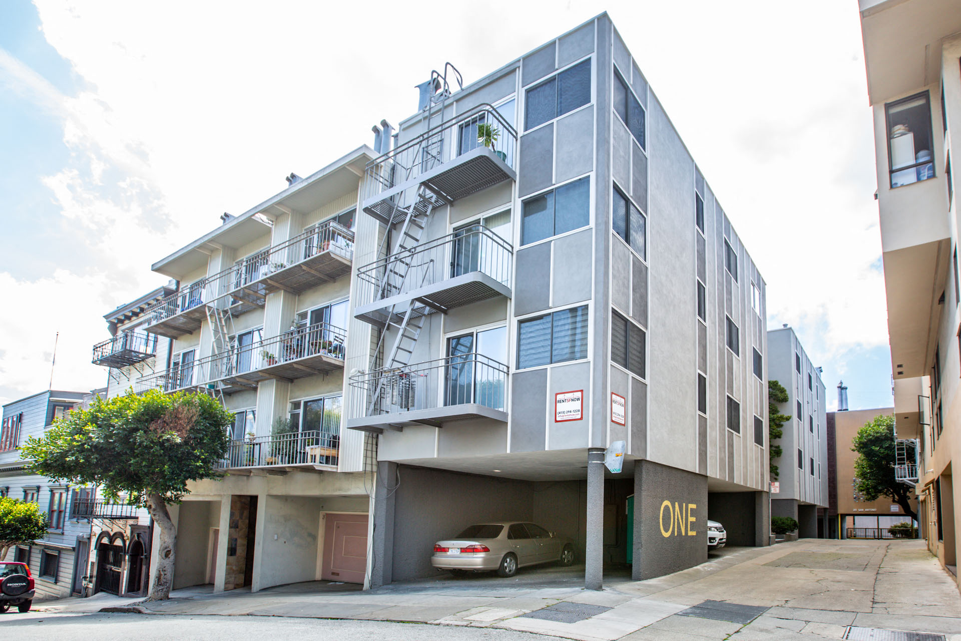 A modern apartment building with a car parked in front.