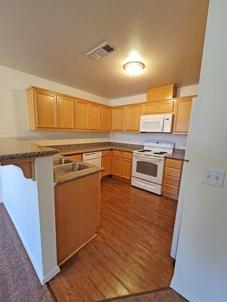 Kitchen showing amenities including , energy efficient stove, overhead microwave, efficient dishwasher and stainless steel sink.  Flooring is woodgrain vinal.