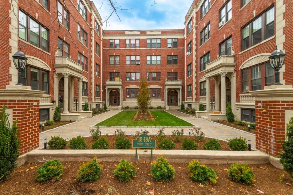 a courtyard between two buildings with a green sign in the middle
