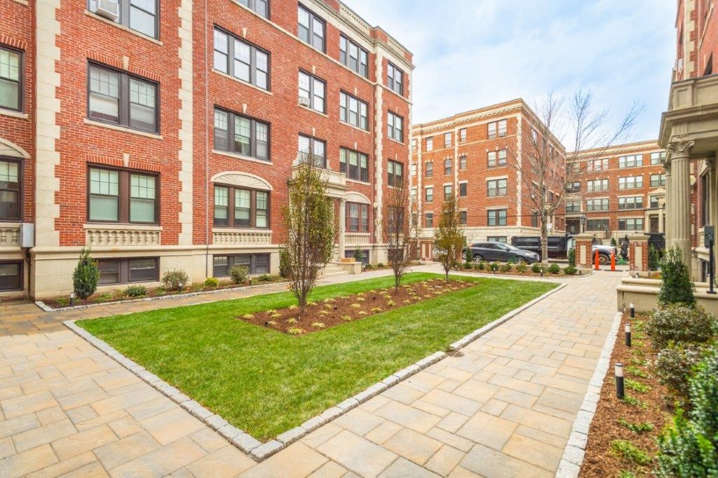 a courtyard with a green lawn in front of a brick building