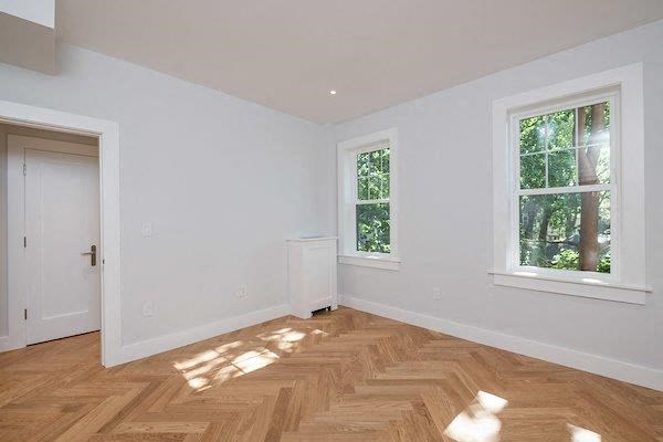 an empty room with a door and two windows