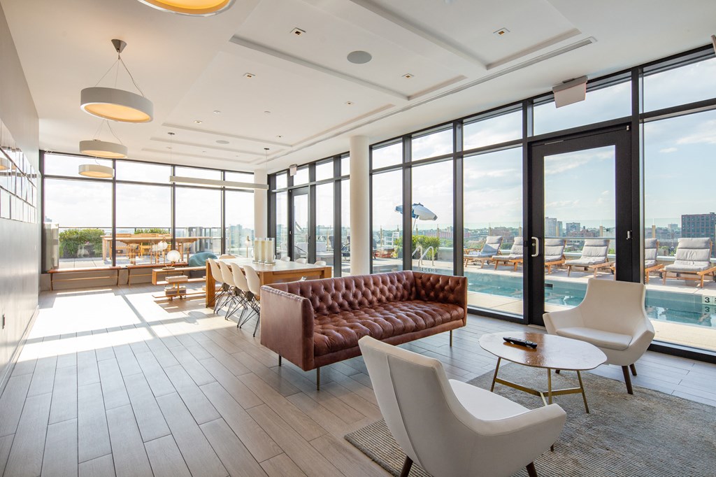a room with couches chairs and a table and a view of a swimming pool