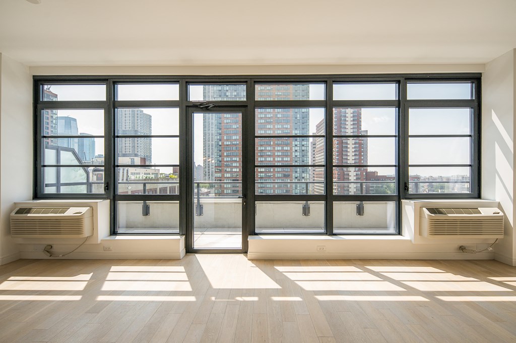 an empty living room with a large window and air conditioning units