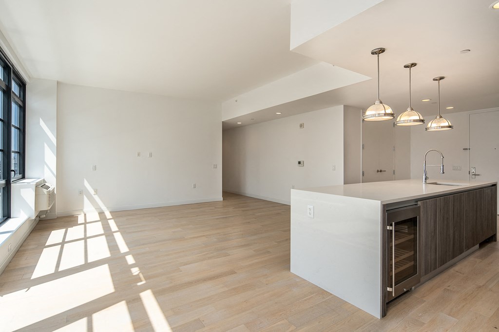 an open kitchen and living room with white walls and wood floors
