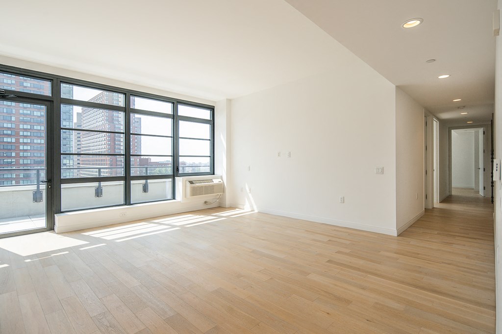 an empty living room with a large window and wood flooring
