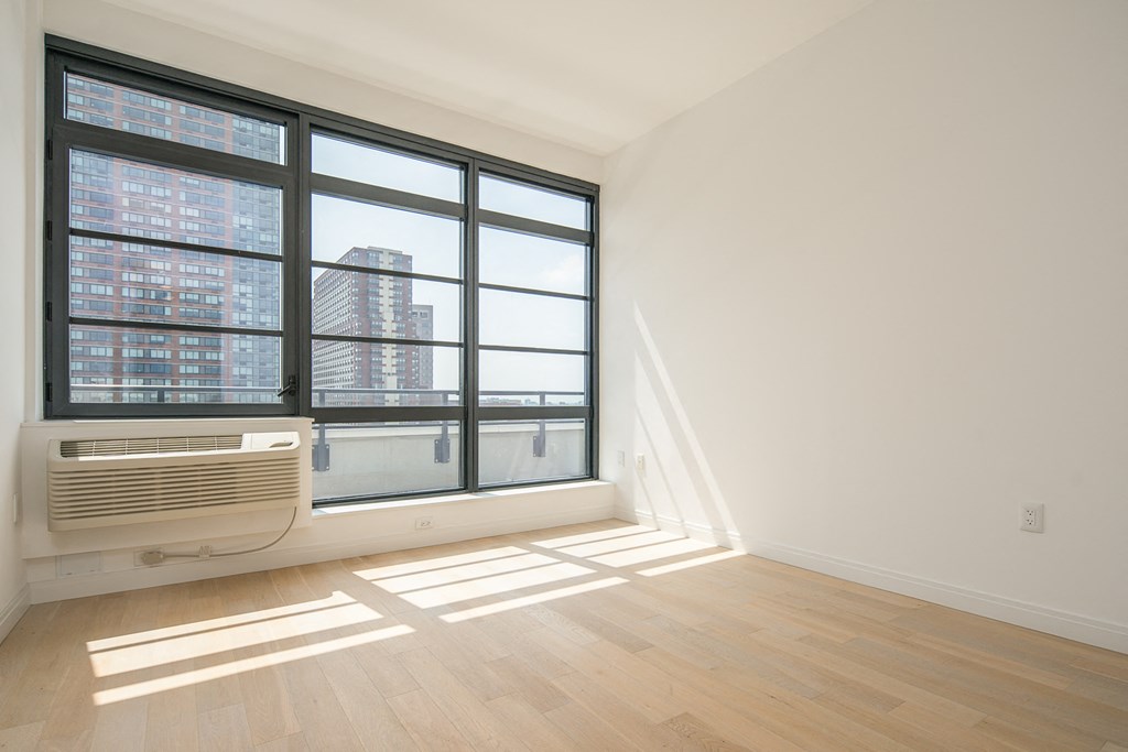 an empty living room with a large window and a radiator on the wall