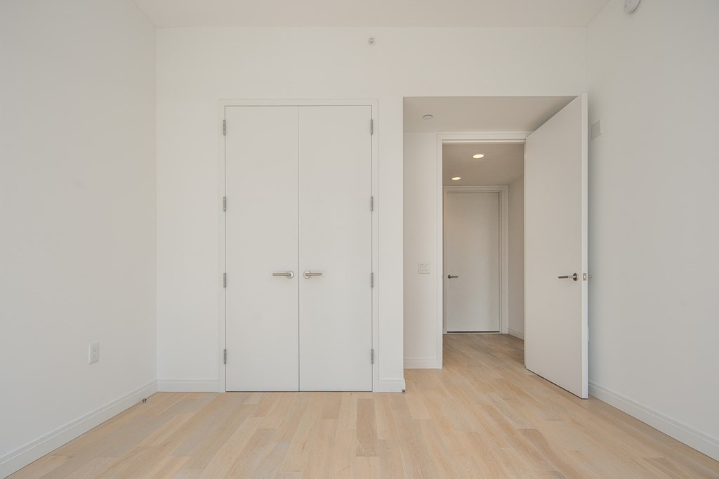 an empty room with white doors and a wooden floor