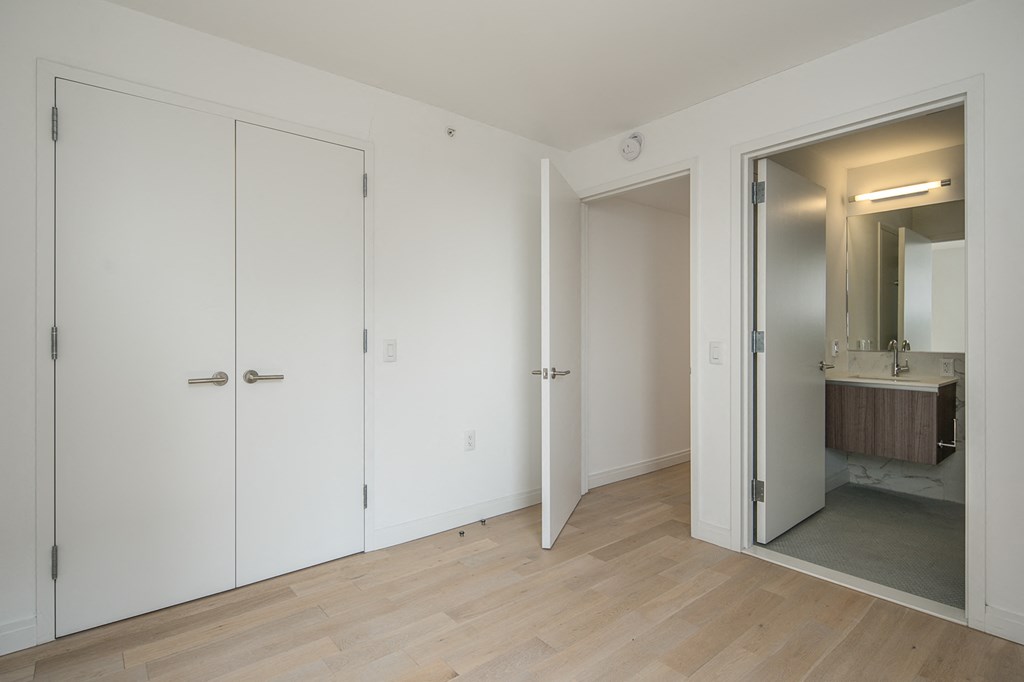 a bedroom with white closets and a bathroom with a mirror