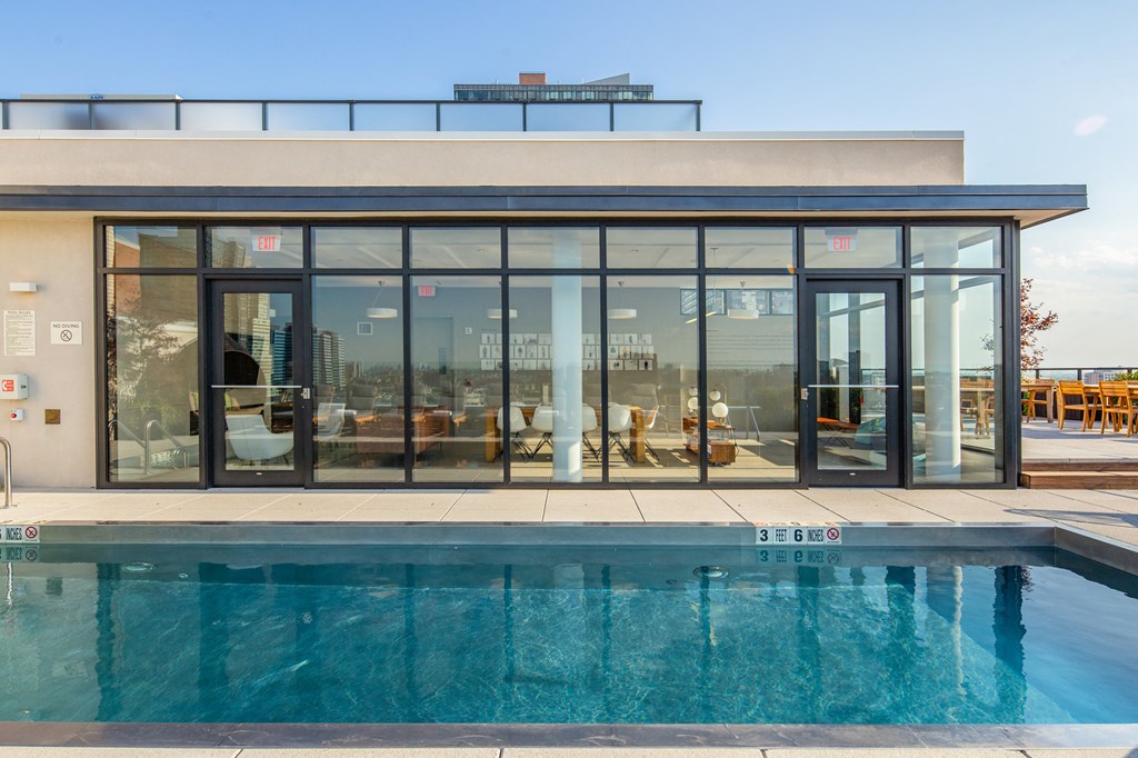 a swimming pool in front of a pool house with glass doors