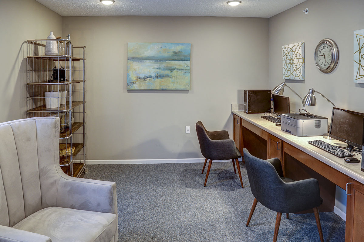 a living room with a computer desk and chairs