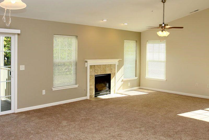 an empty living room with a fireplace and a ceiling fan