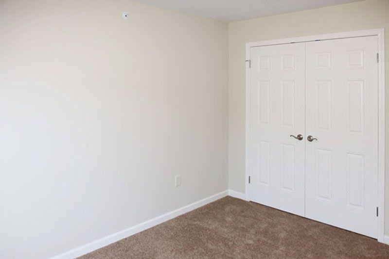 an empty room with two white doors and a carpet