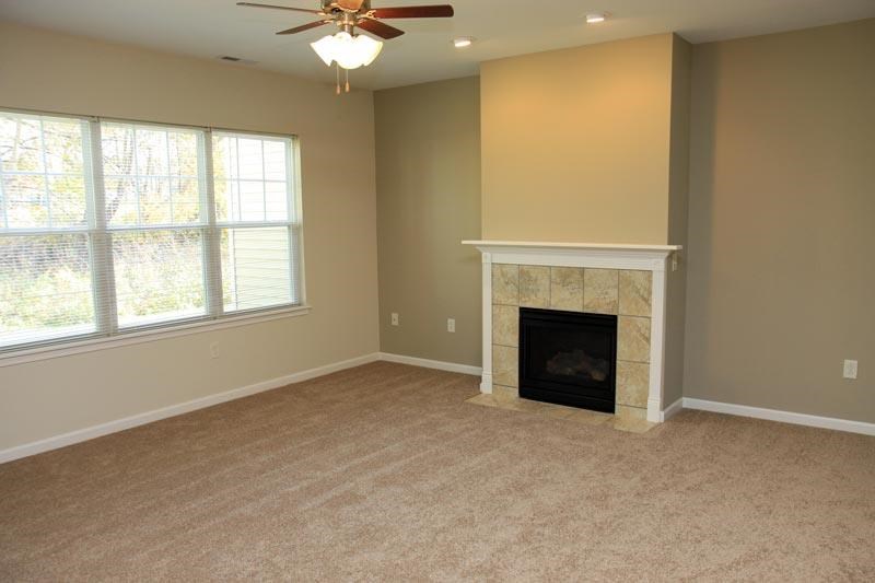 a living room with a fireplace and a ceiling fan