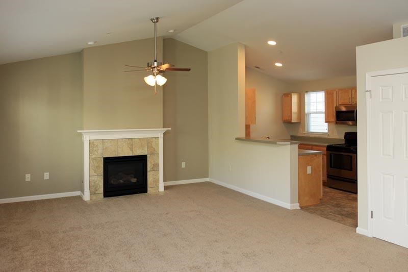 an empty living room with a fireplace and a kitchen