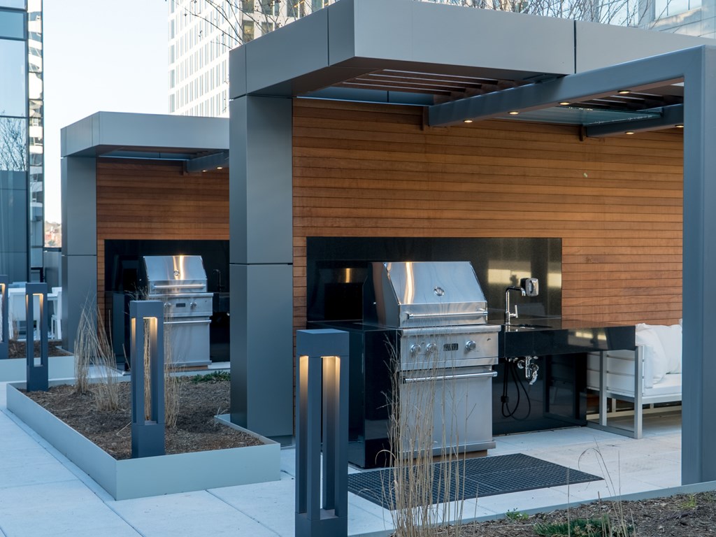 a stainless steel outdoor kitchen with two grills and a wooden facade