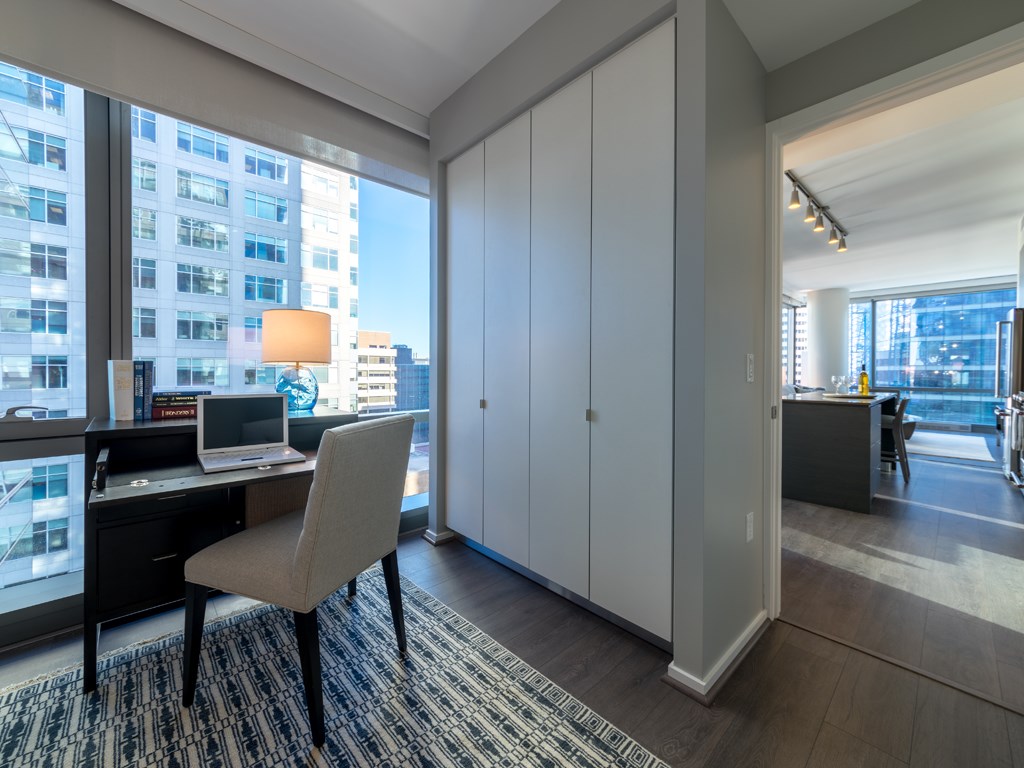 a home office with a desk and a large window