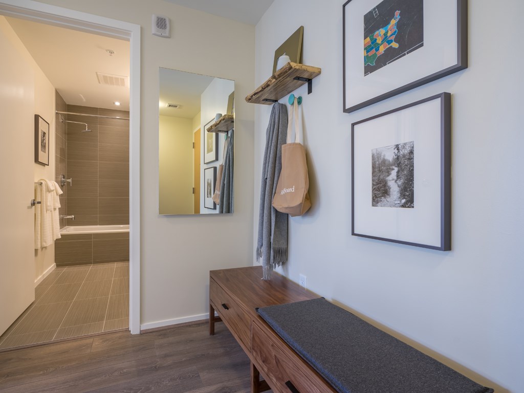 a hallway with a bench and pictures on the wall and a bathroom with a shower