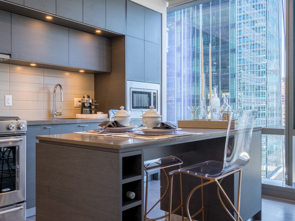 a kitchen with a counter and chairs in front of a window