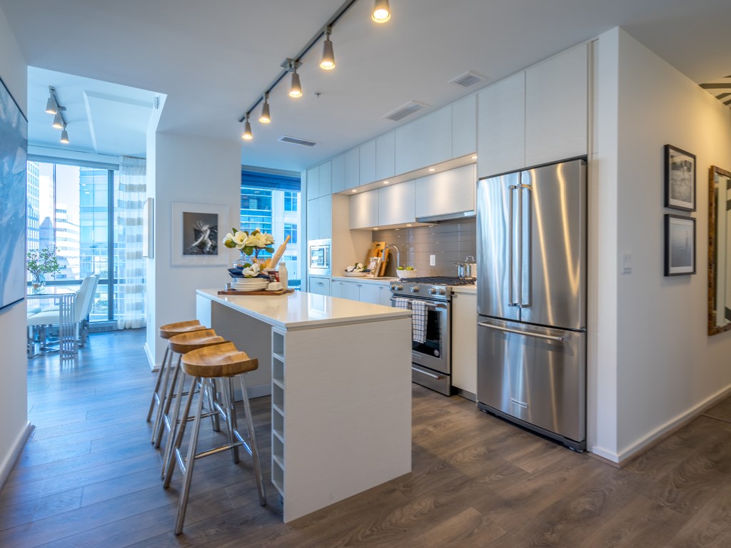 a kitchen with stainless steel appliances and a bar with three stools