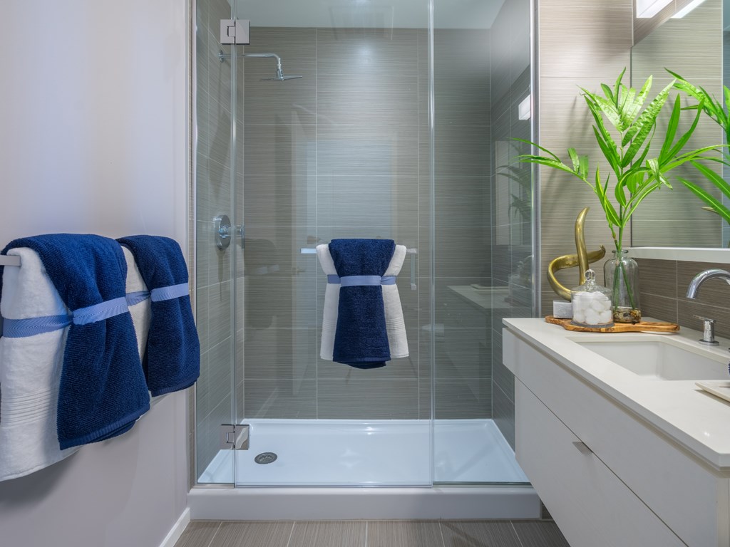 a bathroom with a shower and a sink and blue towels