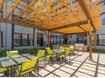 Outdoor BBQ Grill Area with Seating at The Bartram Apartments in Gainesville, FL
