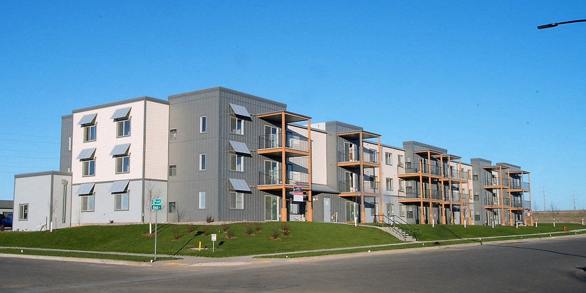 Image of exterior of building, lawn, and road passing by