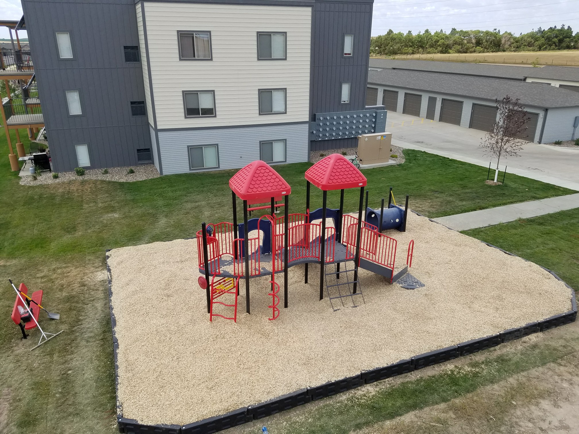 Image of playground in sand on one end of the building